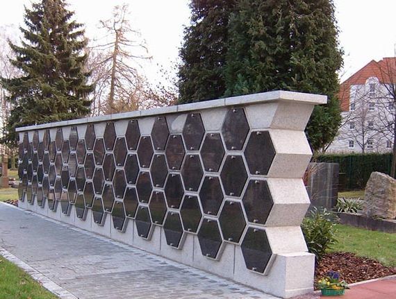 Moderne Gedenkstätte mit hexagonalen schwarzen Platten in ruhiger Parkanlage.