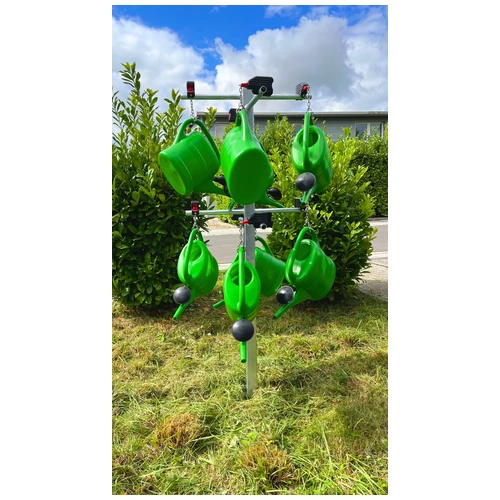 Grüne Windspiel-Gießkannen mit Metallkugeln im Garten.